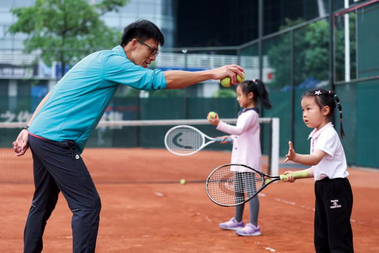 广州。在红土球场参加网球培训的孩子
